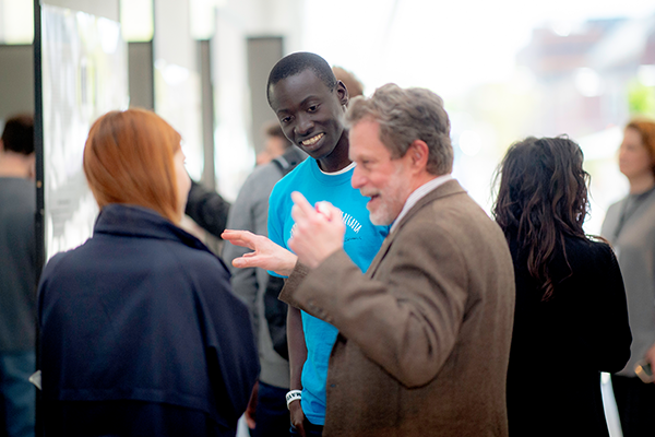 A guest interacts with students at the design fair