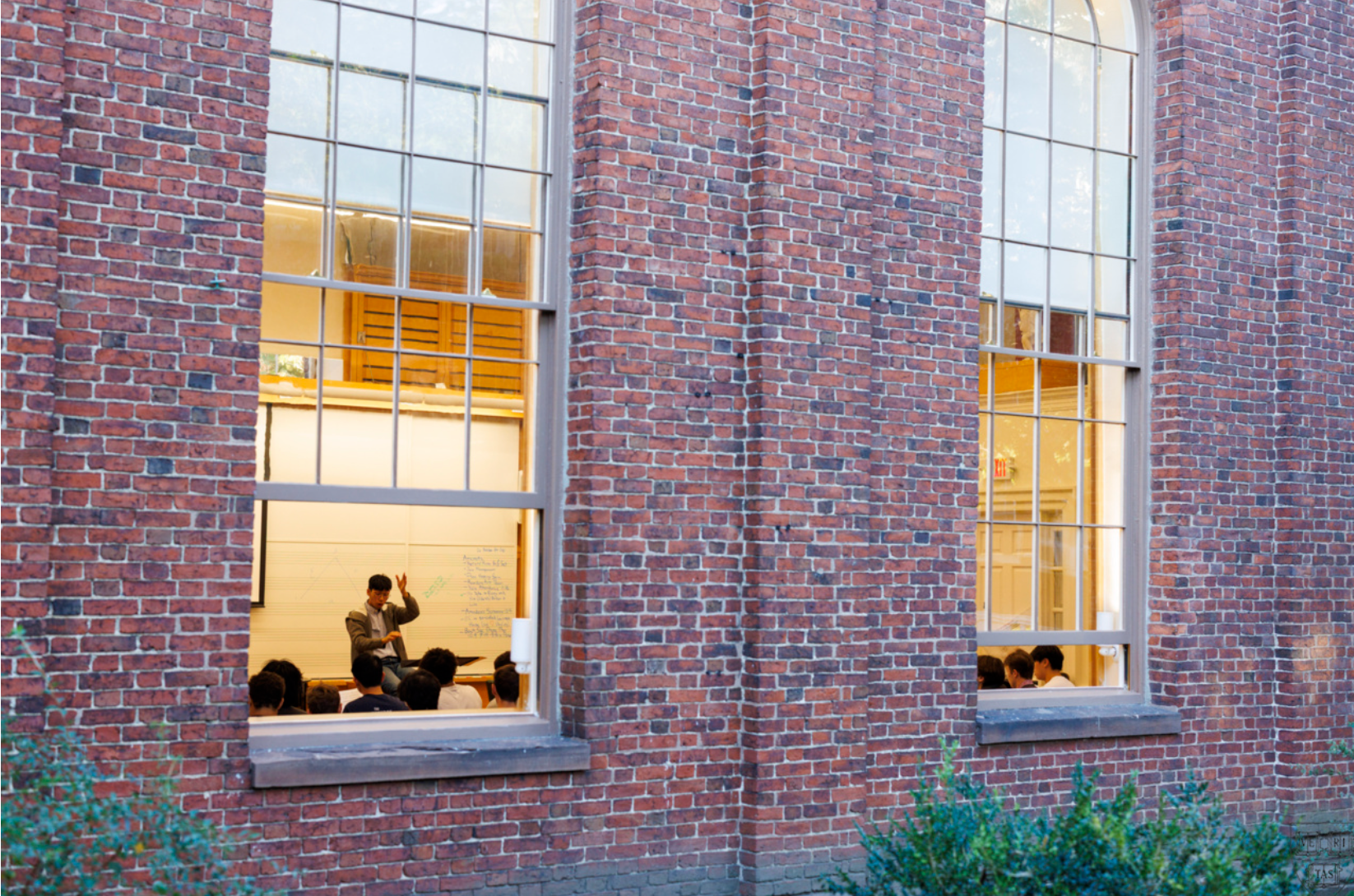 A view through a window into a lecture taking place.