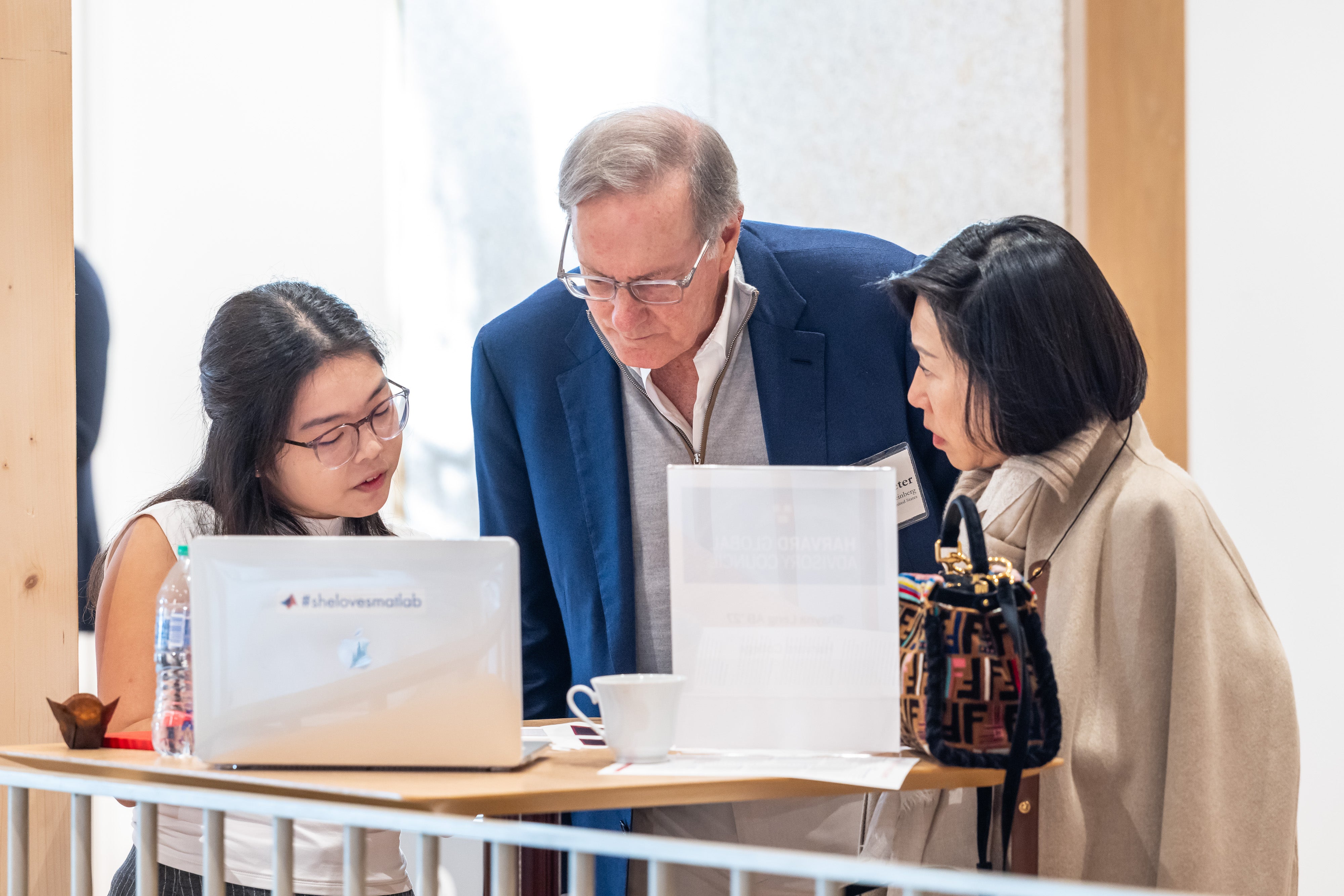 Peter A. Weinberg and Melanie Pong Salata speak with a Harvard student at the 2025 Global Advisory Council meeting.