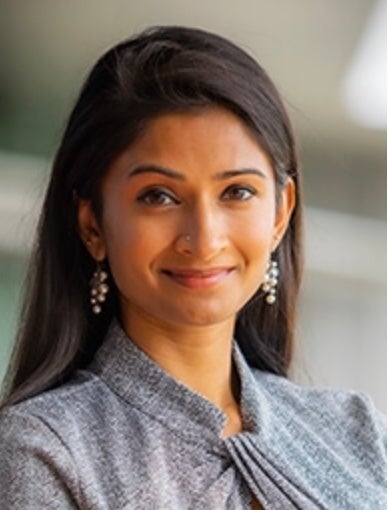 Indian woman wearing a grey sweater with pearl dangling earrings