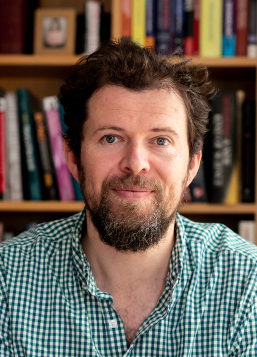 White man with brown hair and a brown beard wearing a collared shirt