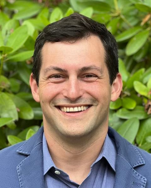 Marc Aidinoff headshot in front of plant