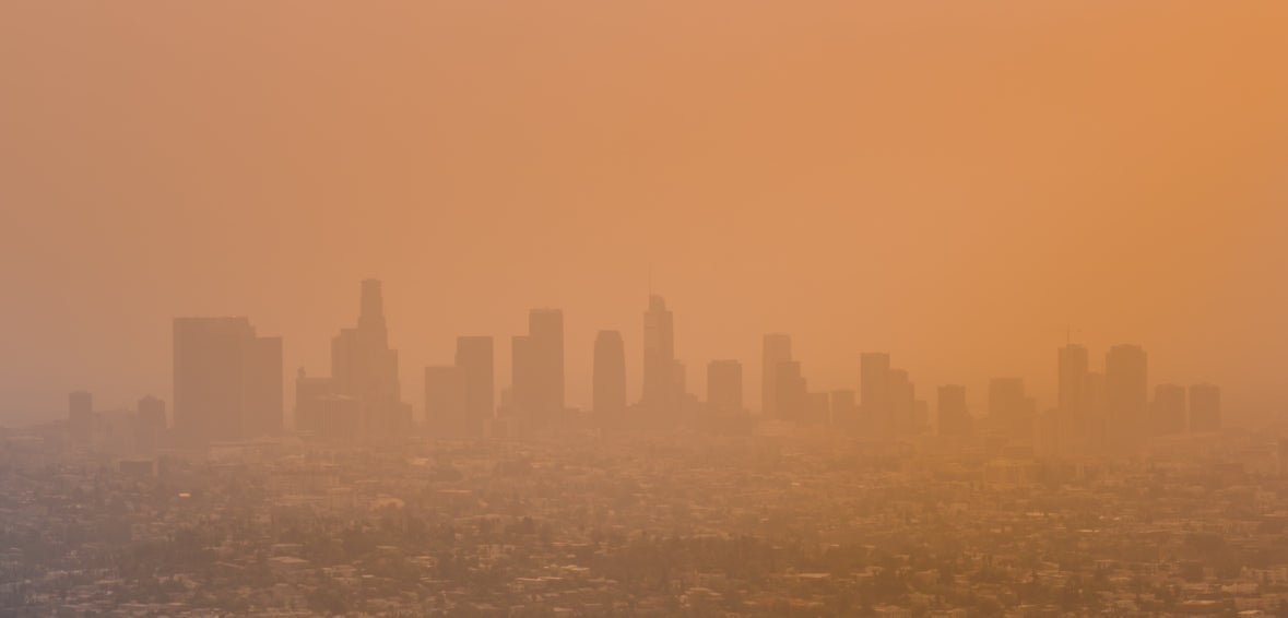 A panoramic view of the Los Angeles skyline with buildings obscured by wildfire smoke and pollutants