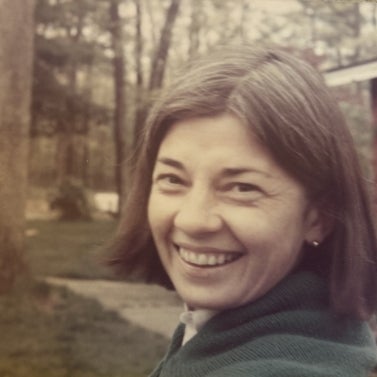 Susan Murphy smiling at the camera with trees and wood in the background