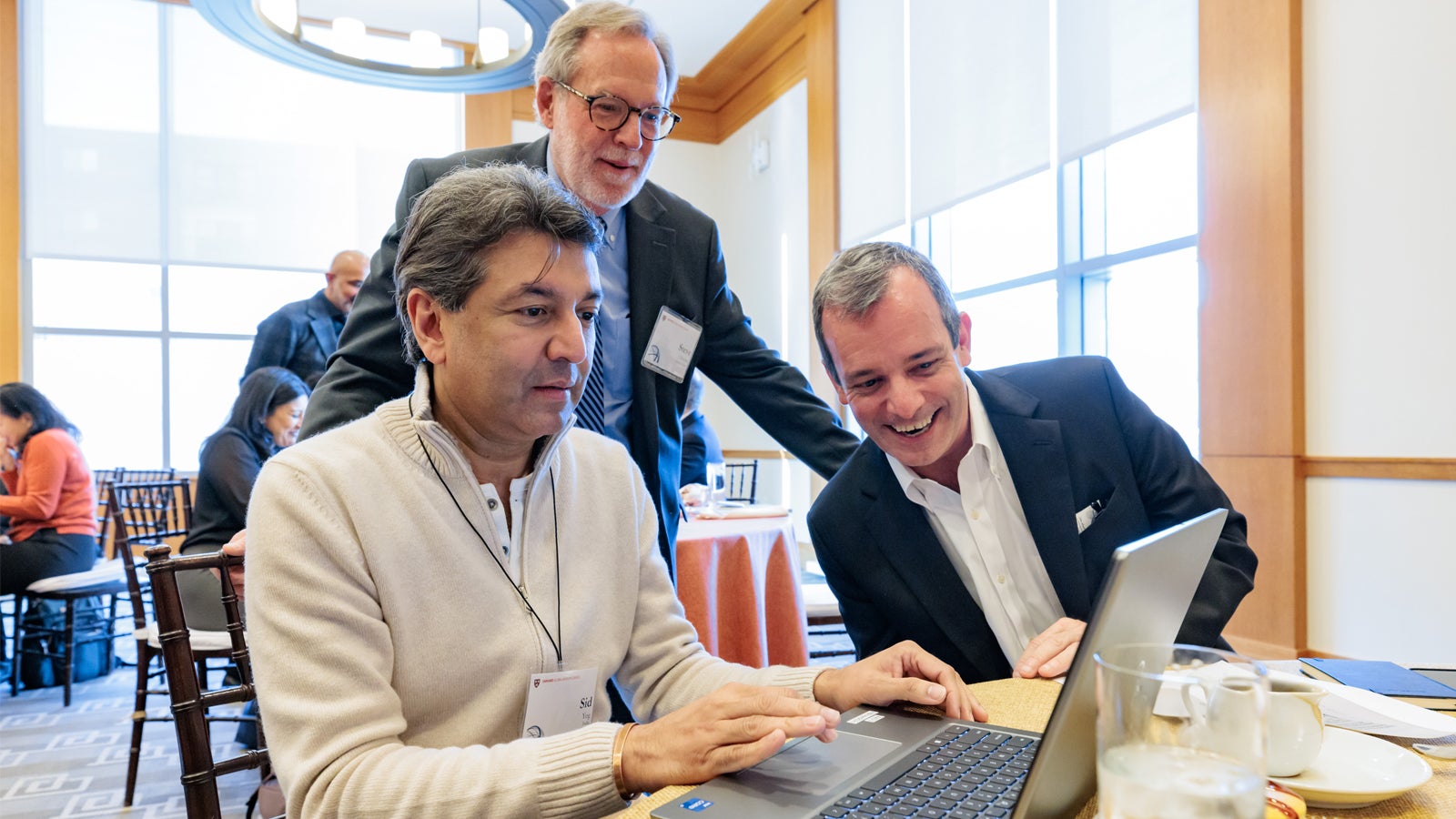 Siddhartha Yog MBA ’04, Steven Oliveira, and Provost John F. Manning AB ’82, JD ’85 participating in a creative exercise to develop their own AI-powered snack company at the 2024 Global Advisory Council meeting.