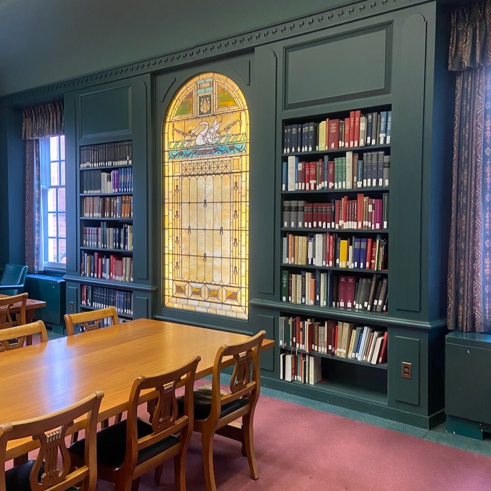 Library with stain glass windows and books in built in book shelves 