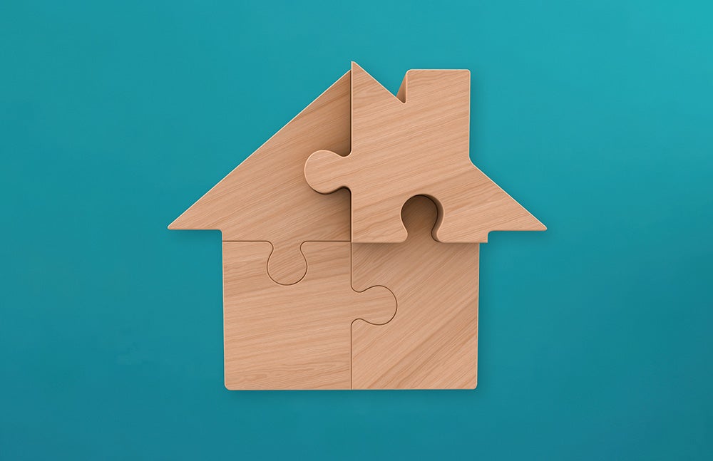 A house-shaped puzzle constructed with four interlocking wooden pieces against a teal background