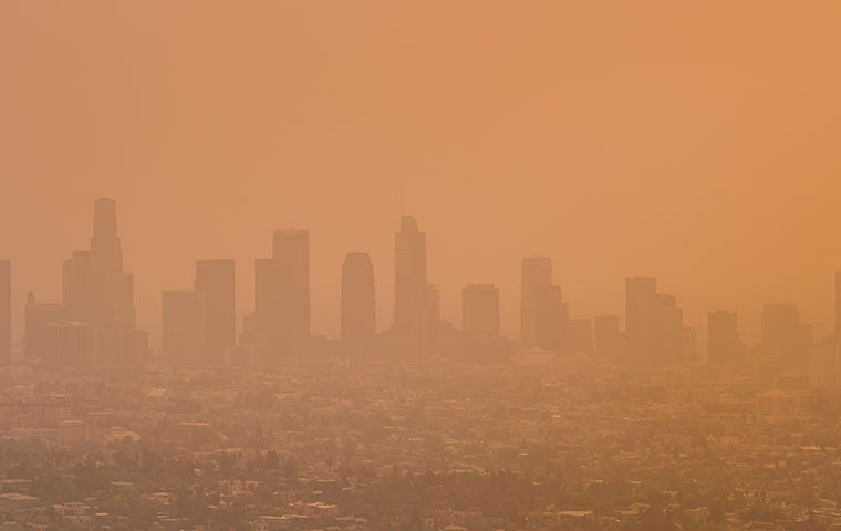 A panoramic view of the Los Angeles skyline with buildings obscured by wildfire smoke and pollutants
