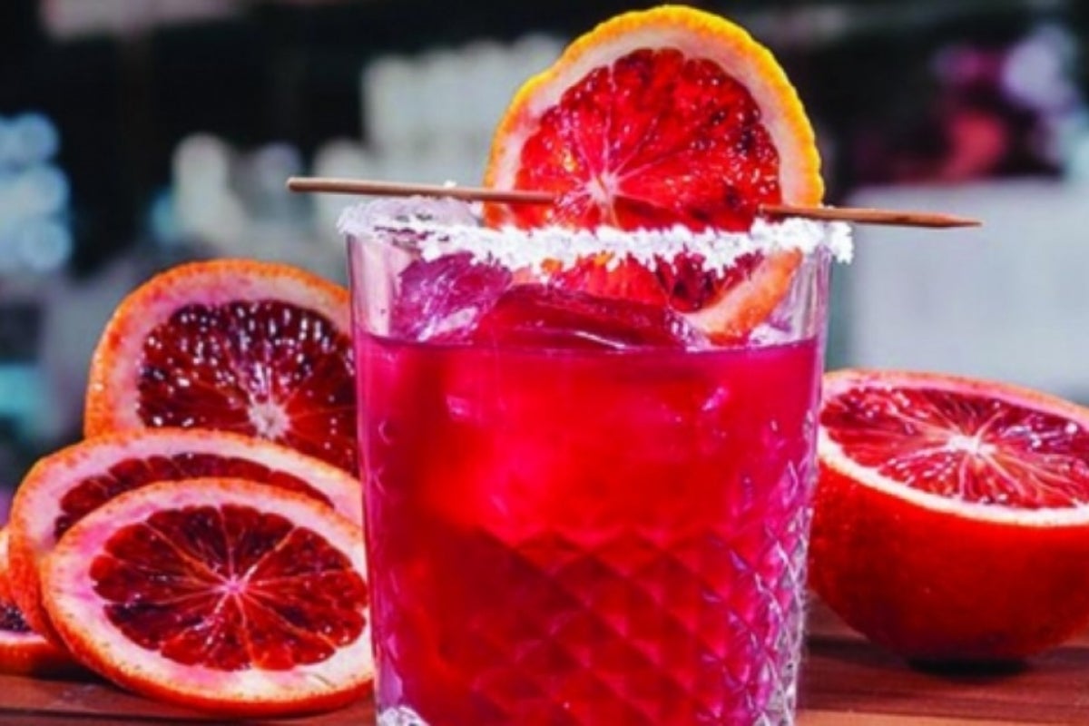 Image of a cocktail in a short glass with salt rim and a slice of blood orange