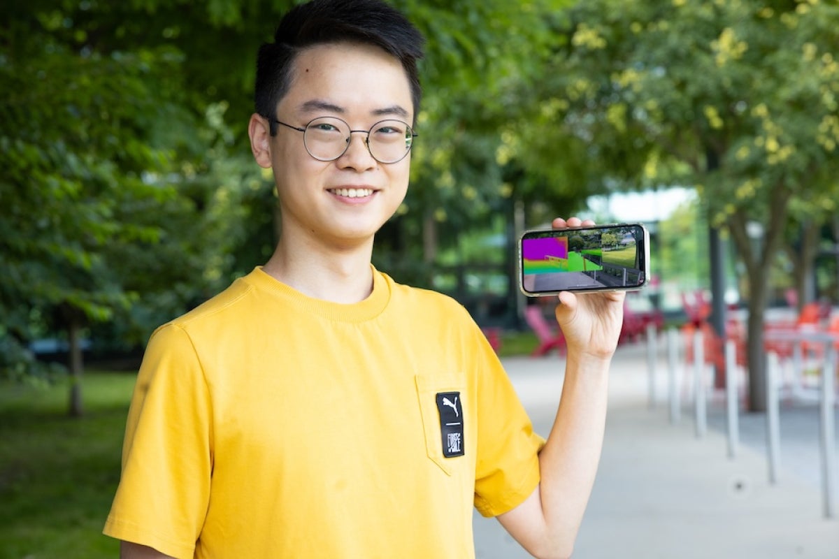 Raymond Liu holding a cell phone displaying an app for the visually impaired