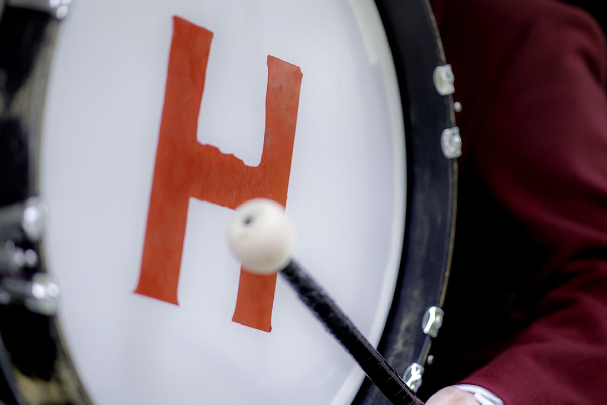 Student playing Harvard-branded marching band drum