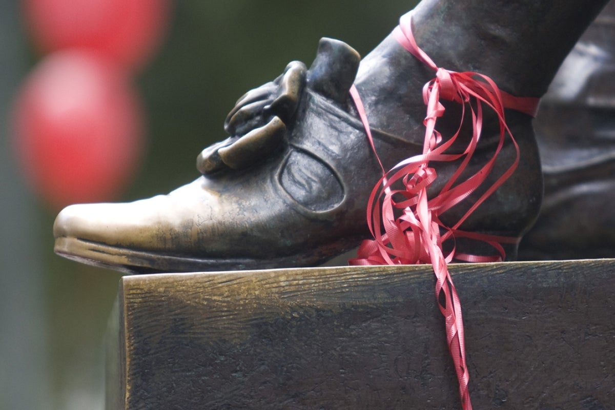 Image of John Harvard Statues' foot adorned with red ribbon