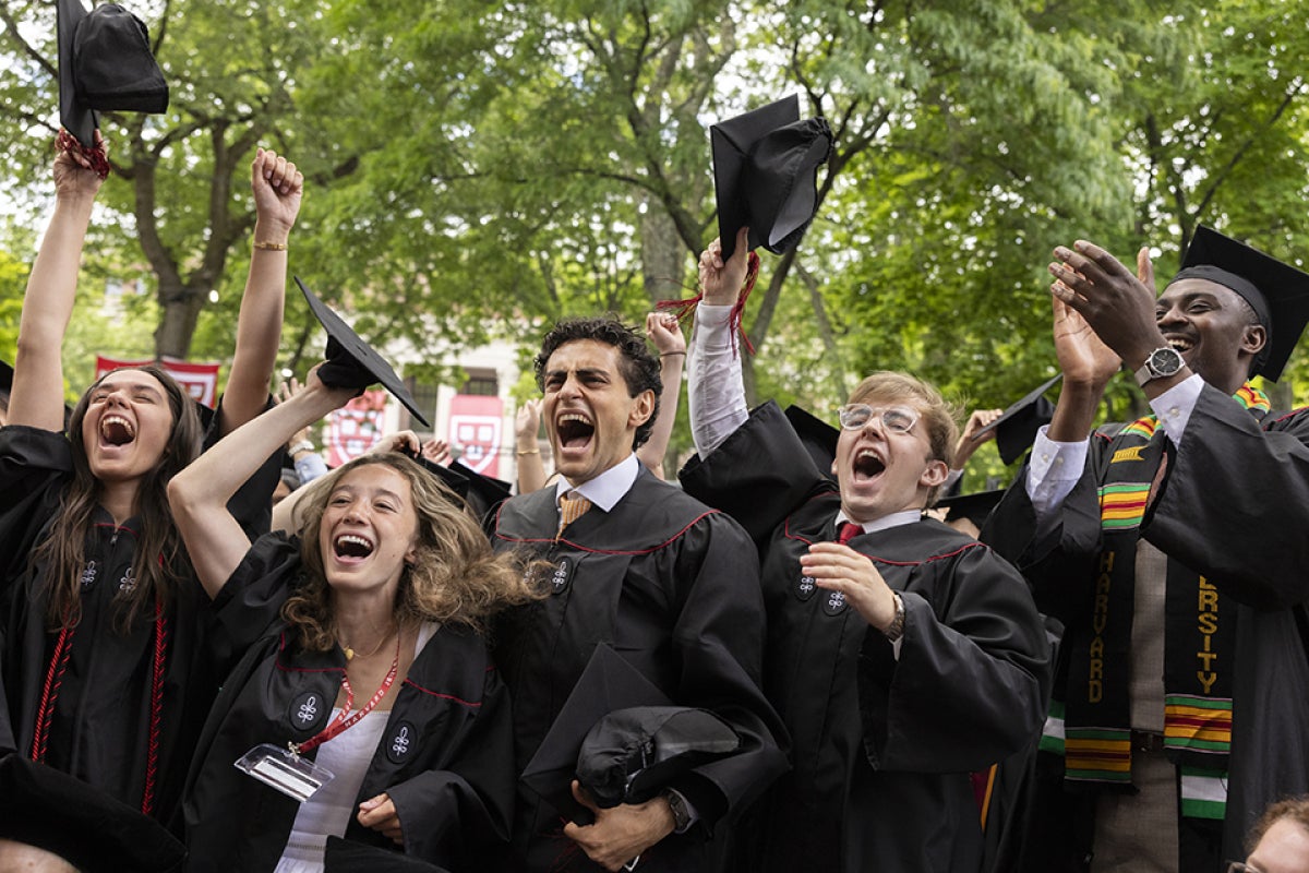 Five graduates jump in joy after conferring their degrees during Commencement