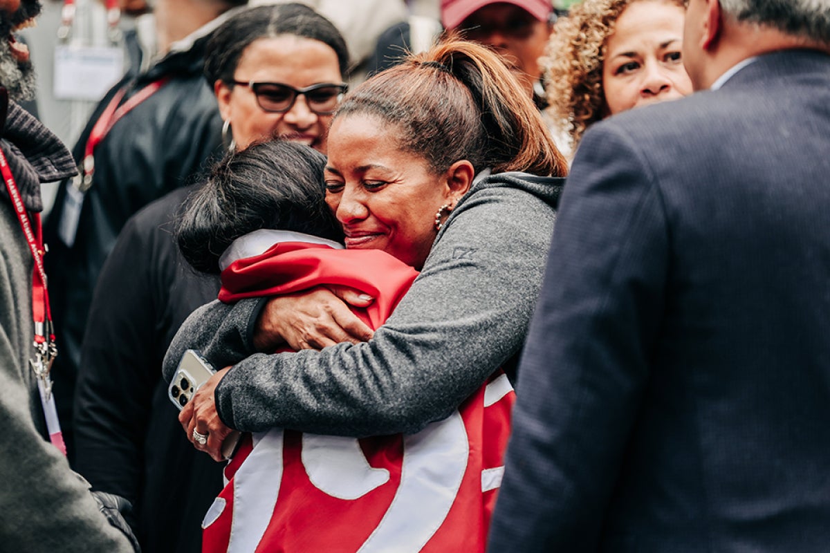 alumna in reunion embracing classmate wrapped in class banner