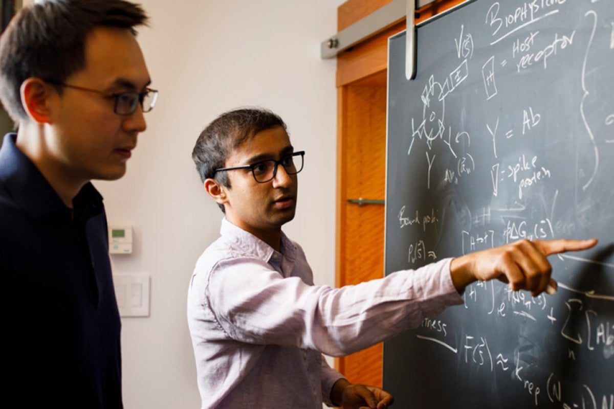 Two students solve an equation on a chalkboard