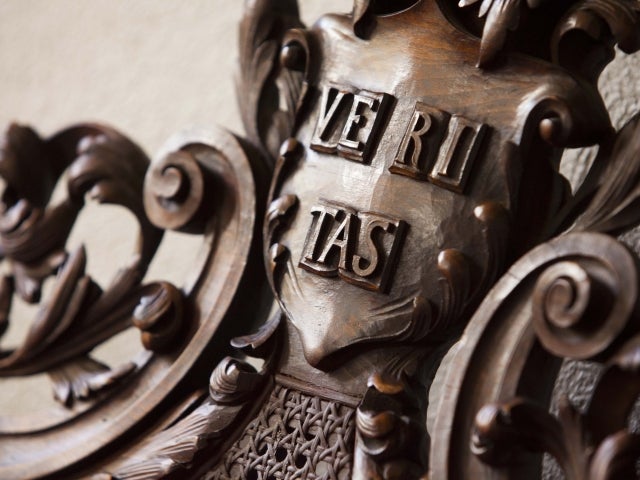 Close-up of an ornate wooden carving featuring the Latin word "VERITAS" on a shield.
