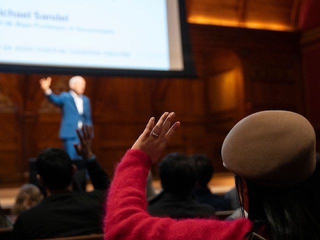 A person raises their hand to ask a question during a lecture