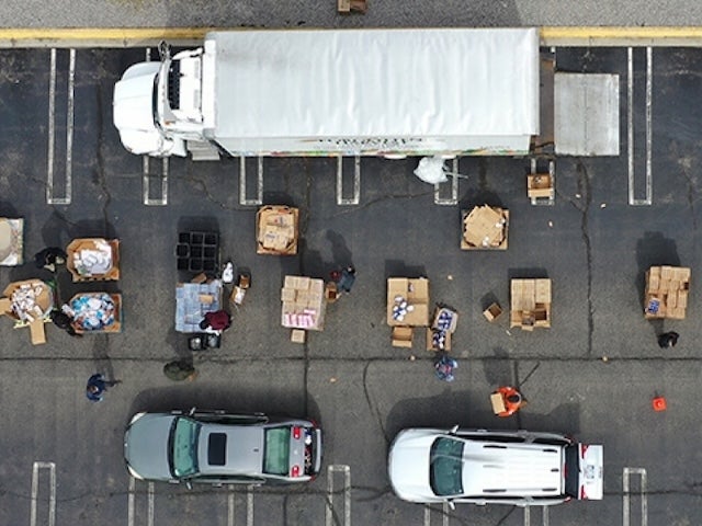 People loading and unloading boxes of goods in a parking lot