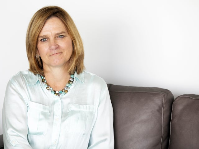A headshot of Karen Johnson sitting on a brown leather couch