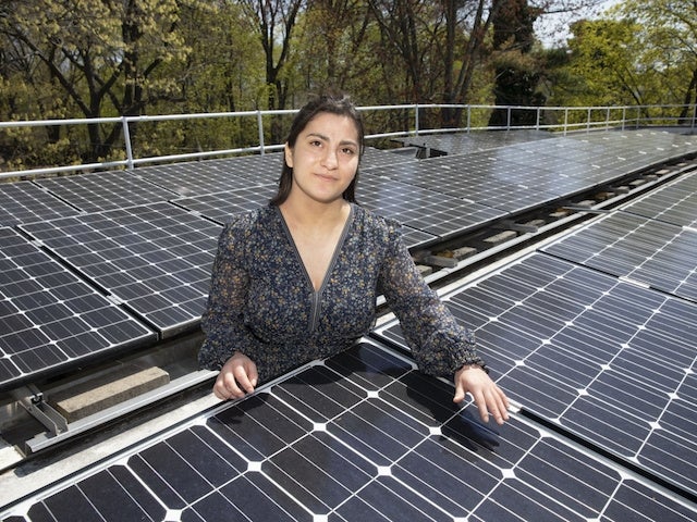 Maggie Vallejo stands among an array of solar panels