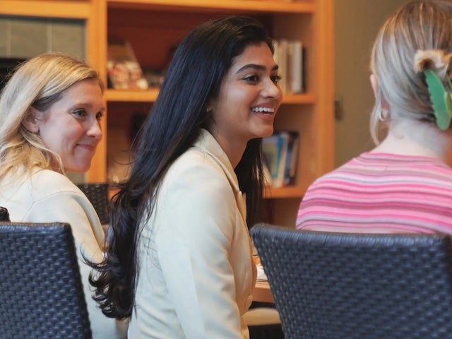 Students sit and talk around a table