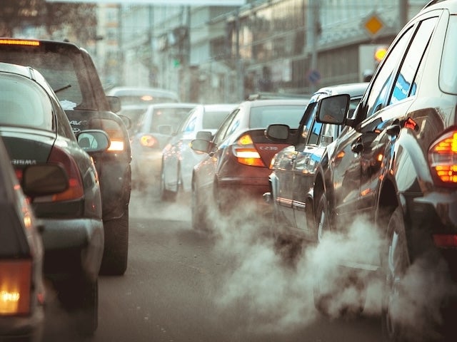 Emissions emanate from a line of cars in traffic on a city street