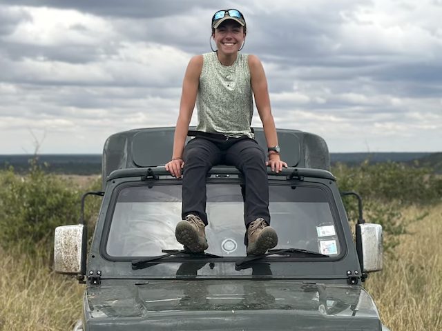 Lucrecia Aguilar sitting on top of a dark green SUV in Kenya