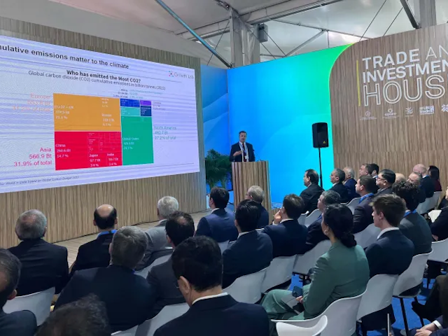 Presentation at a conference discussing emissions, with a chart on screen 