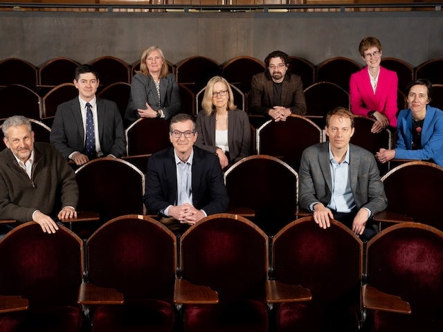 Several Harvard faculty members sit in a classroom