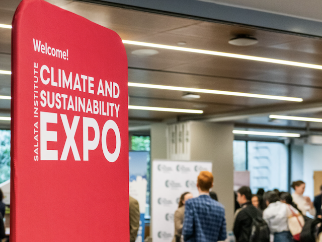 A group of people in a room, with a large red sign that says "Welcome, Salata Institute Climate and Sustainability Expo"