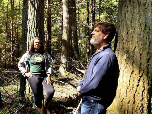 Keshia De Freece Lawrence and Neil Pederson stand among the trees in Harvard Forest 