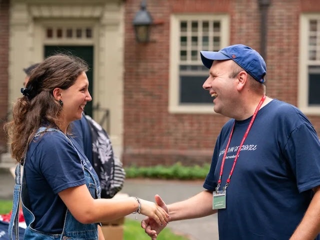  Two people shake hands and smile in Harvard Yard