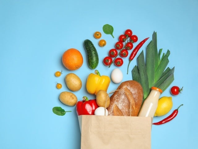 Shopping paper bag with different groceries on light blue background