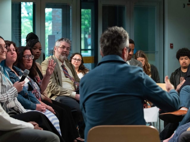 A diverse group of individuals seated in a semi-circle, engaging in a discussion