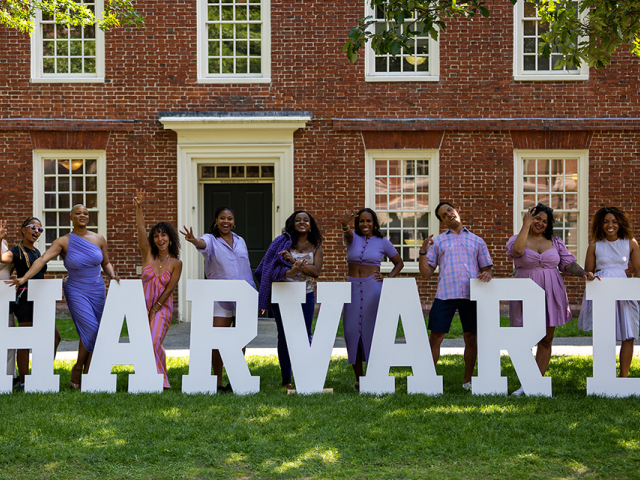 Harvard Alumni Day attendees pictured with block letters spelling HARVARD in the Yard
