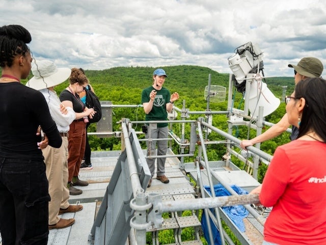 Harvard Forest senior scientist Jackie Matthes speaks to the tour group at the top of a 120-foot research tower, which provides panoramic views of the surrounding forest