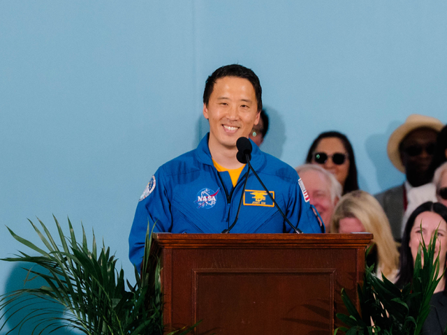 Dr Jonny Kim on stage at podium delivering keynote address on Harvard Alumni Day
