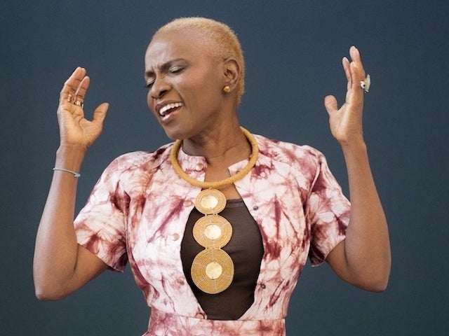 Angélique Kidjo holding up her hands while singing