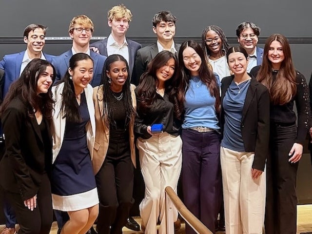 A group of students pose with a small blue device
