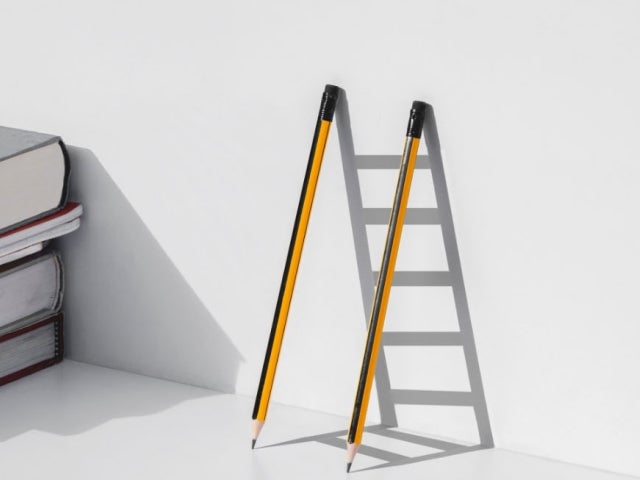 Two pencils leaning on a wall leaving a shadow of a ruler