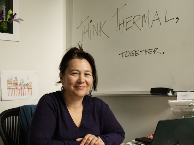 Zeyneb Magavi in her office, sitting in front of a white board that says “Think Thermal, Together”