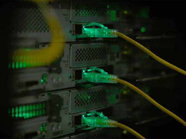 Green-lit servers with several connected yellow cables