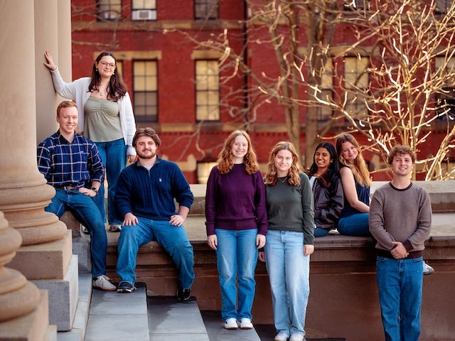 Eight Harvard students pose together on the steps of a campus building