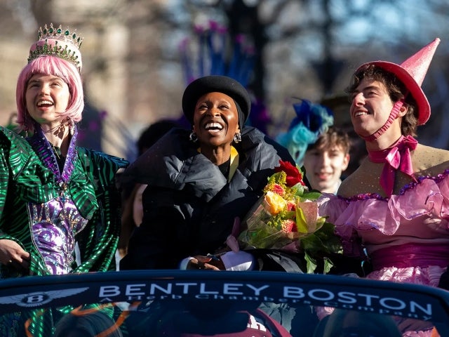 Cynthia Erivo and two Hasty Pudding Theatricals students in costume laugh and look up during the parade