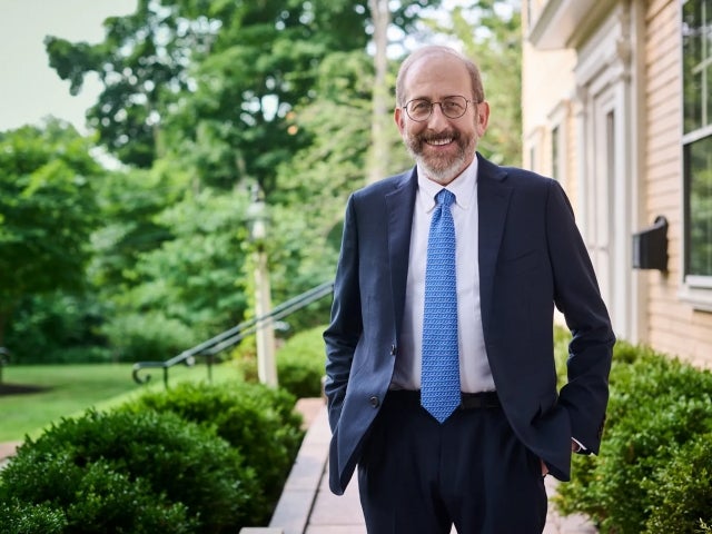 Alan Garber stands outdoors on a path lined with bushes