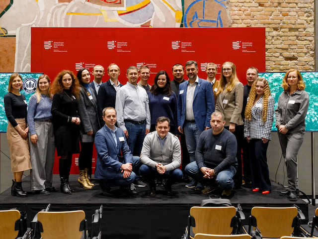 Group photo of professionals standing in front of a red backdrop at an event