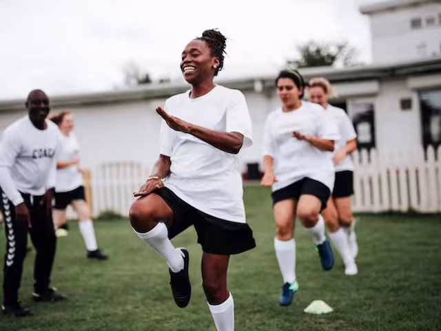 Several women athletes warming up on a grassy field