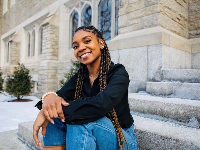 Aliyah Collins sits on the steps outside a building at Harvard Divinity School 