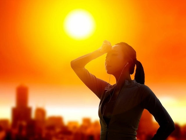 Woman wiping sweat off her forehead in the glare of the sun