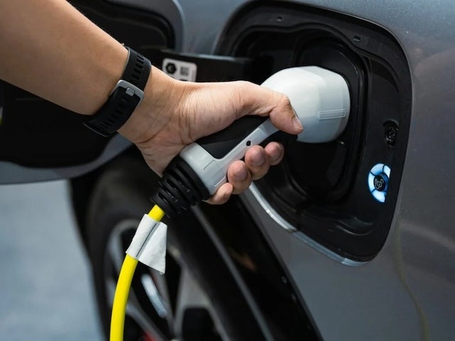 Close up of a hand plugging a charger into an electric vehicle
